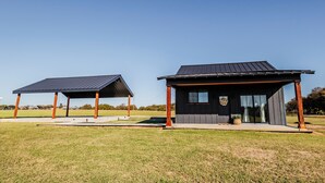 A modern building with a covered outdoor area, a large window, and a door. - Charming 1-bedroom cottage in serene countryside (Blum)