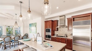 A modern kitchen with a central island, stainless steel appliances, wooden cabinets, and pendant lighting. - Luxury 4-bedroom Penthouse in Siesta Key- Private rooftop terrace (Siesta Key)