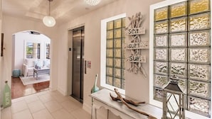 A hallway with a modern kitchen area, a refrigerator, and a dining table with chairs. - Luxury 4-bedroom Penthouse in Siesta Key- Private rooftop terrace (Siesta Key)
