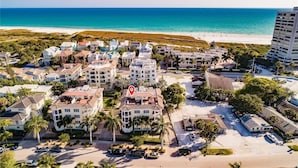 A coastal residential area with a beachfront view, featuring multi-story buildings, parking areas, and a prominent hotel with a red location marker. - Luxury 4-bedroom Penthouse in Siesta Key- Private rooftop terrace (Siesta Key)