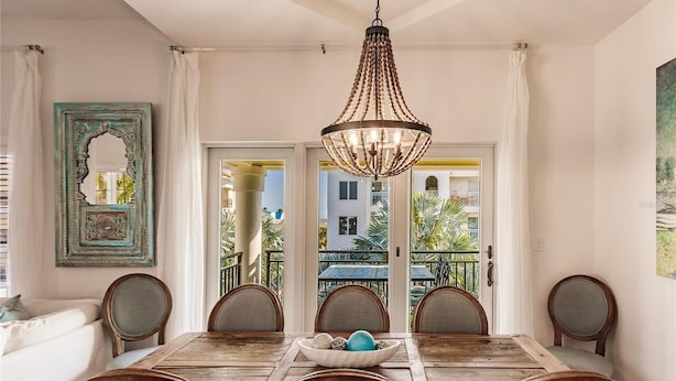 A dining area with a wooden table and chairs, a chandelier, and a view of a balcony with plants. - Luxury 4-bedroom Penthouse in Siesta Key- Private rooftop terrace (Siesta Key)