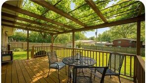 A wooden deck with a pergola, a round table, and two chairs. - Base yourselves here!  3 bes+2ba w/ great yard, dual monitor workstation! (Lawrence)