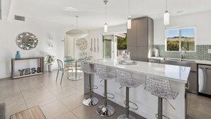 Een moderne keuken met een groot schiereiland, barstoelen en hanglampen.