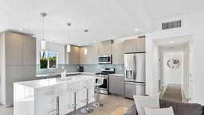 Een moderne keuken met een centraal eiland, roestvrijstalen apparatuur en hanglampen.
