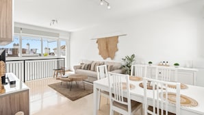 A modern kitchen with white cabinetry, a dining area with white tables and chairs, and a large window overlooking a cityscape. - Luxury Penthouse • Rooftop • Sea views • Private Parking (Estepona)