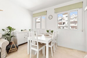A white dining area with a table set for four, surrounded by chairs, a clock on the wall, and windows with curtains. - Luxury Penthouse • Rooftop •  Sea views • Private Parking (Estepona)