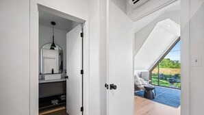 En modern inredning med badrum, ett matområde med utsikt mot utomhusmiljön och ett rymligt rum med ett stort fönster.