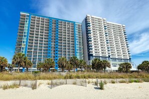 A high-rise hotel with multiple floors, a blue and white color scheme, and a beach view. - Beachfront Boardwalk Condo (Myrtle Beach)
