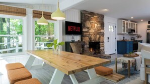 Een moderne keuken met een stenen openhaard, een houten eettafel en een televisie erboven bevestigd.