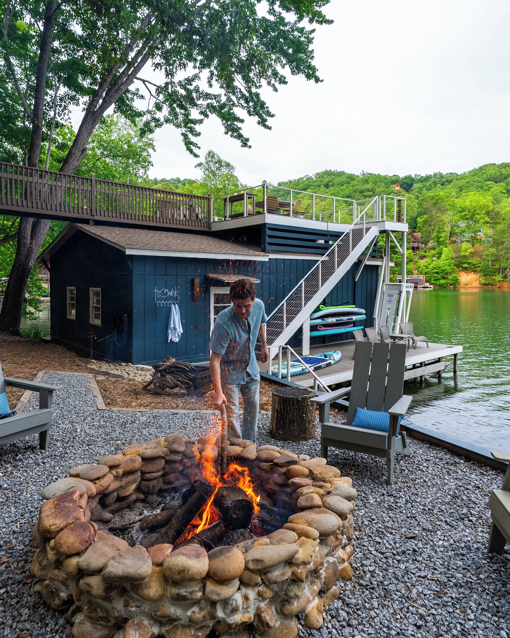 Une terrasse au bord du lac, avec un foyer, des sièges d’extérieur et un quai avec des bateaux.