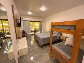 Ett modernt hotellrum med två våningssängar, ett skrivbord, en stol och ett litet bord.