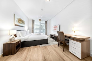 Ein modernes Hotelzimmer mit Bett, Schreibtisch, Stuhl und dem Schild 'BOOK ME'.