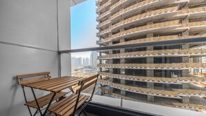 A balcony with a wooden table and chairs, overlooking a multi-story parking garage with construction scaffolding. - Stayshort - 2 Bed in Dubai Marina That Sleeps 5 (Dubai)