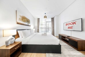 Ein modernes Hotelzimmer mit einem großen Bett, einem Flachbildfernseher, einem Gemälde und einem Schild mit der Aufschrift 'BOOK ME'.