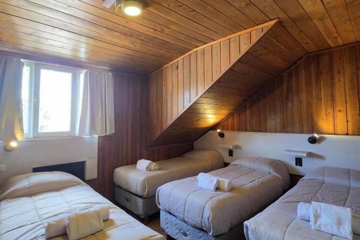 Une pièce avec trois lits, des murs en bois, un plafond en pente et une fenêtre.