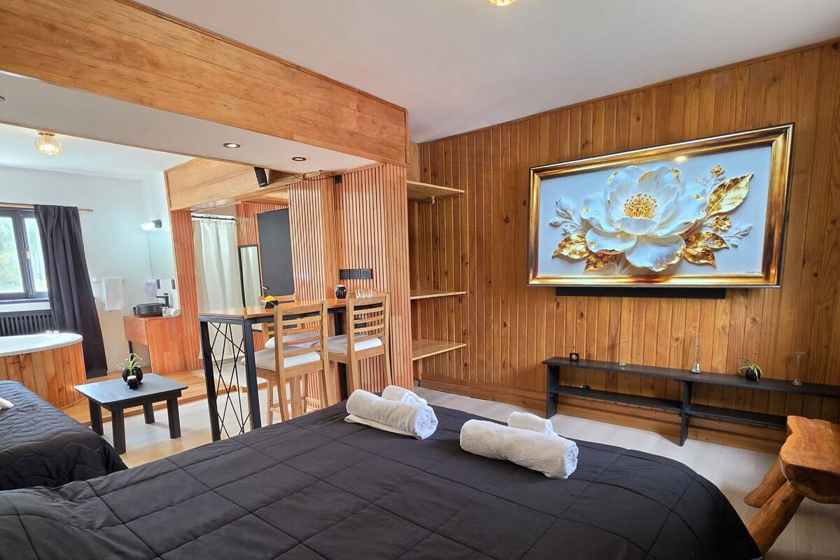 Une chambre d’hôtel avec un grand lit, un bureau, une chaise, un banc et un tableau accroché au mur.