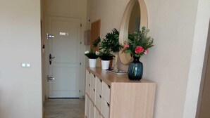 A hallway with a light wooden bench, potted plants, and a mirror on the wall. - Your best vacations in Mijas (Mijas)