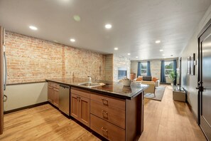 Una cocina moderna con pared de ladrillo, armarios de madera y una isla grande.