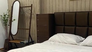 A bedroom with a large bed, a dresser, a mirror, and a painting on the wall. - 4U Resort & Camp (Yaring)
