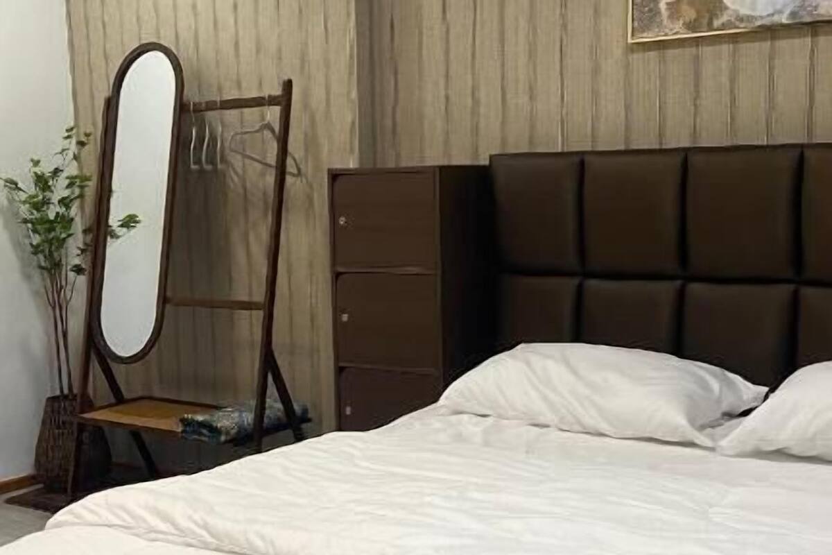 A bedroom with a large bed, a dresser, a mirror, and a painting on the wall.