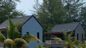 Two blue buildings with a sandy ground and palm trees in a tropical setting. - 4U Resort & Camp (Yaring)