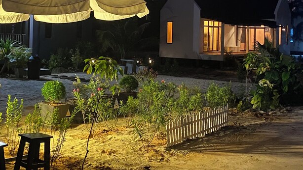 A beachside property with a large umbrella, a small house, and a sandy area with plants. - 4U Resort & Camp (Yaring)