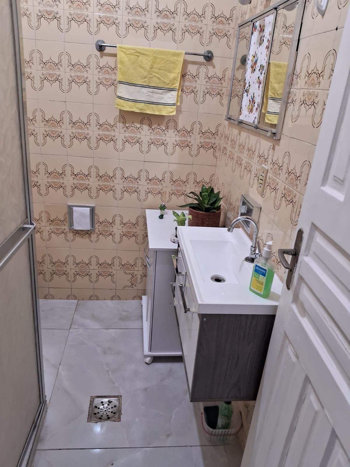 A small bathroom with patterned tiles, a sink, a mirror, and a towel rack.