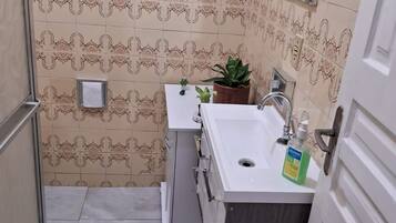 A small bathroom with patterned tiles, a sink, a mirror, and a towel rack.