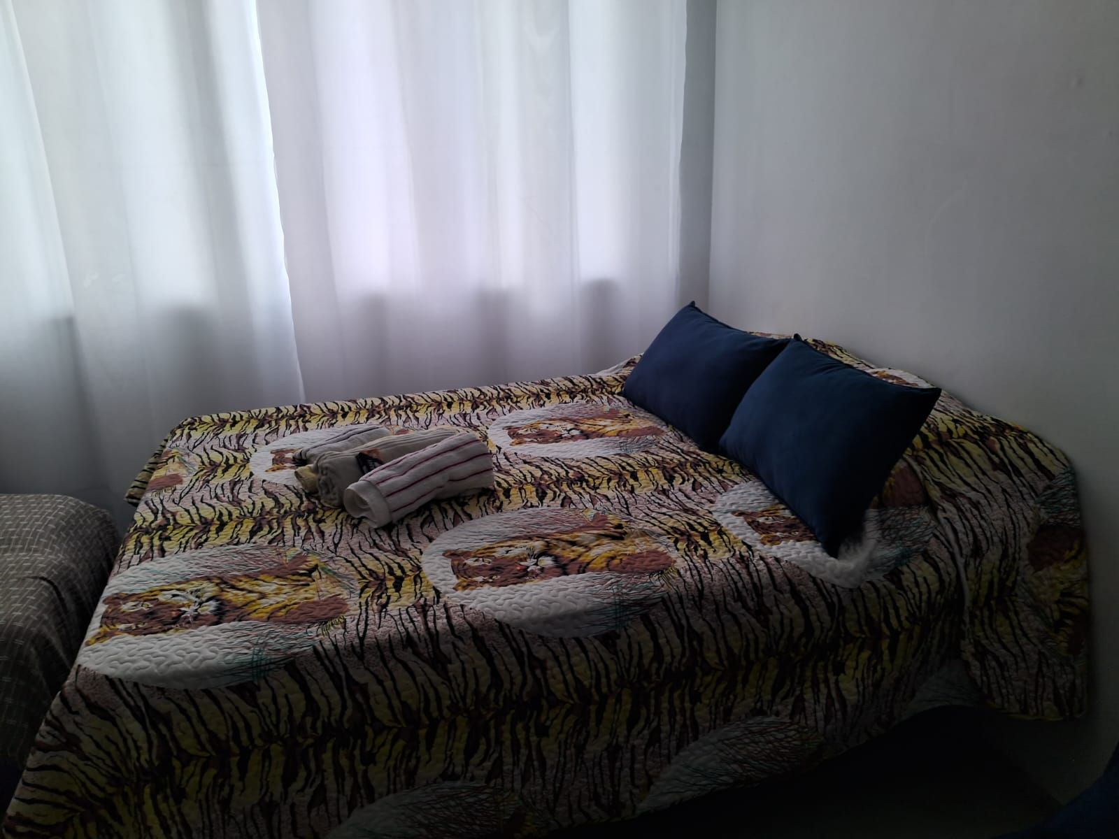 A bed with a patterned bedspread, two pillows, and folded towels.