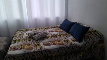 A bed with a patterned bedspread, two pillows, and folded towels.