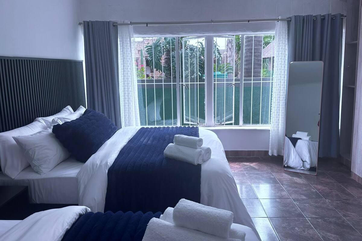 Habitación de hotel con una cama grande, una ventana con vistas a la vegetación y un armario.