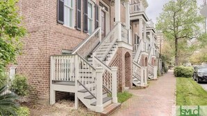 Una hilera de casas urbanas de ladrillo con barandillas blancas y escaleras que conducen a la entrada.