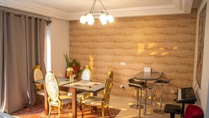 Zona pranzo con parete in legno, un lampadario, un tavolo da pranzo con sedie e un divano rosso.