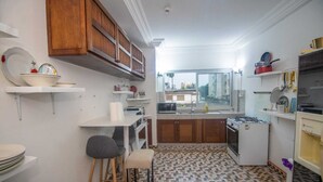 Una cucina compatta con mobili in legno, un piano di lavoro bianco e un pavimento decorato.