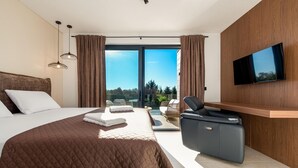 Quarto de hotel moderno com uma cama grande, poltrona de massagem, TV de tela plana e varanda com vista para árvores.
