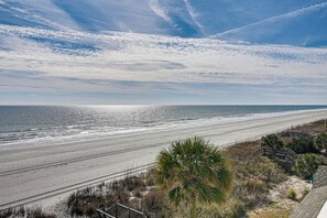A beach view with a clear sky, sandy beach, and a palm tree. - Steps to Pool & Beach: Coastal Carolina Condo! (Surfside Beach)