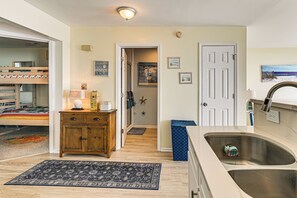 A well-lit kitchen with a sink, wooden cabinets, and a rug on the floor. - Steps to Pool & Beach: Coastal Carolina Condo! (Surfside Beach)