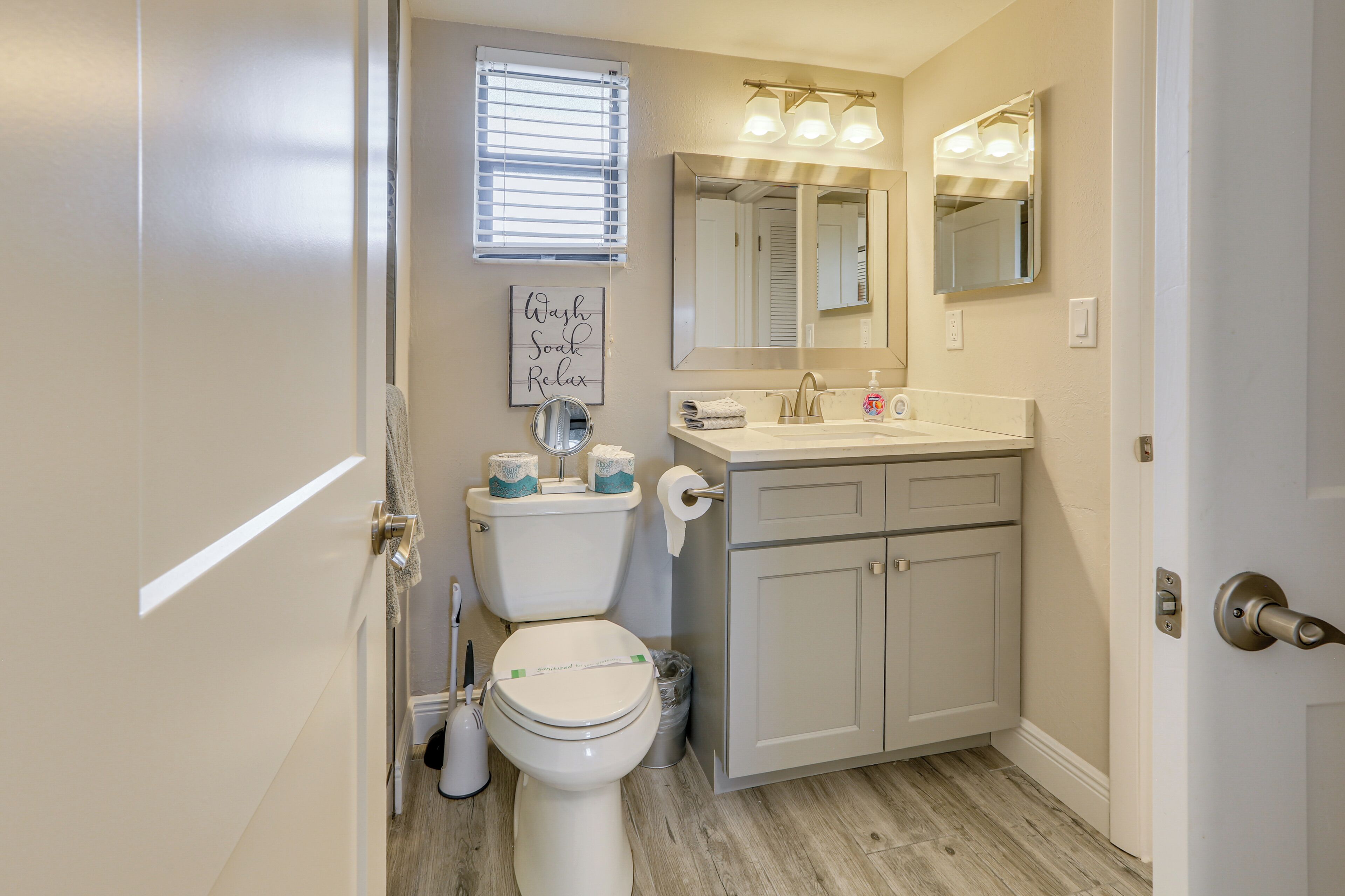 Een badkamer met toilet, wastafel en spiegel. Op de muur staat een bordje met de tekst 'Wash Sock Relax'.