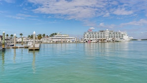 A marina with several boats docked, a large white building with multiple decks, and a clear blue sky with scattered clouds. - 2 Mi to Tigertail Beach! Resort-Style Gem w/ Pool (Marco Island)