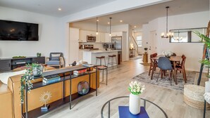 Un soggiorno moderno con zona pranzo, cucina e una scala che conduce a un altro livello.