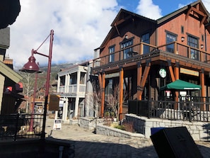 A wooden building with a Starbucks Coffee sign, a bell, and a sign for a ski lift. - Whistler Creekside Retreat • King Bed • Step to Gondola • Outdoor Pool & Hot Tub (Whistler)