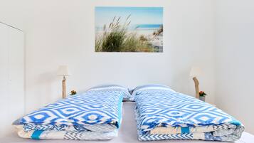 A bed with a patterned blanket and two bedside lamps.