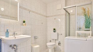 Une salle de bain moderne équipée d’un lavabo, de toilettes et d’une zone douche.