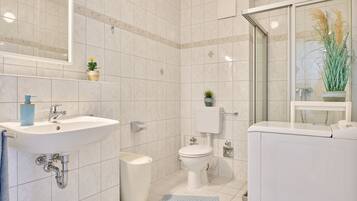 A modern bathroom with a sink, toilet, and shower area.