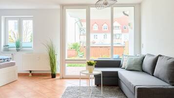 A modern living room with a grey sofa, a small white table, and a potted plant.