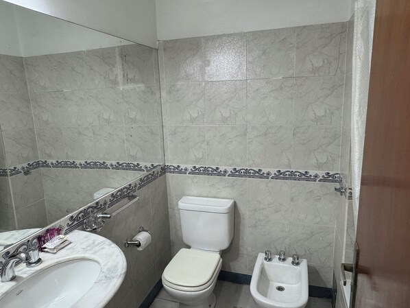 Un baño con lavamanos de mármol, inodoro, bidé y azulejos decorativos.