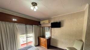 A hotel room with a bed, a chair, a TV, and a window with curtains. - Hotel Quebrada de Humahuaca (San Salvador de Jujuy)