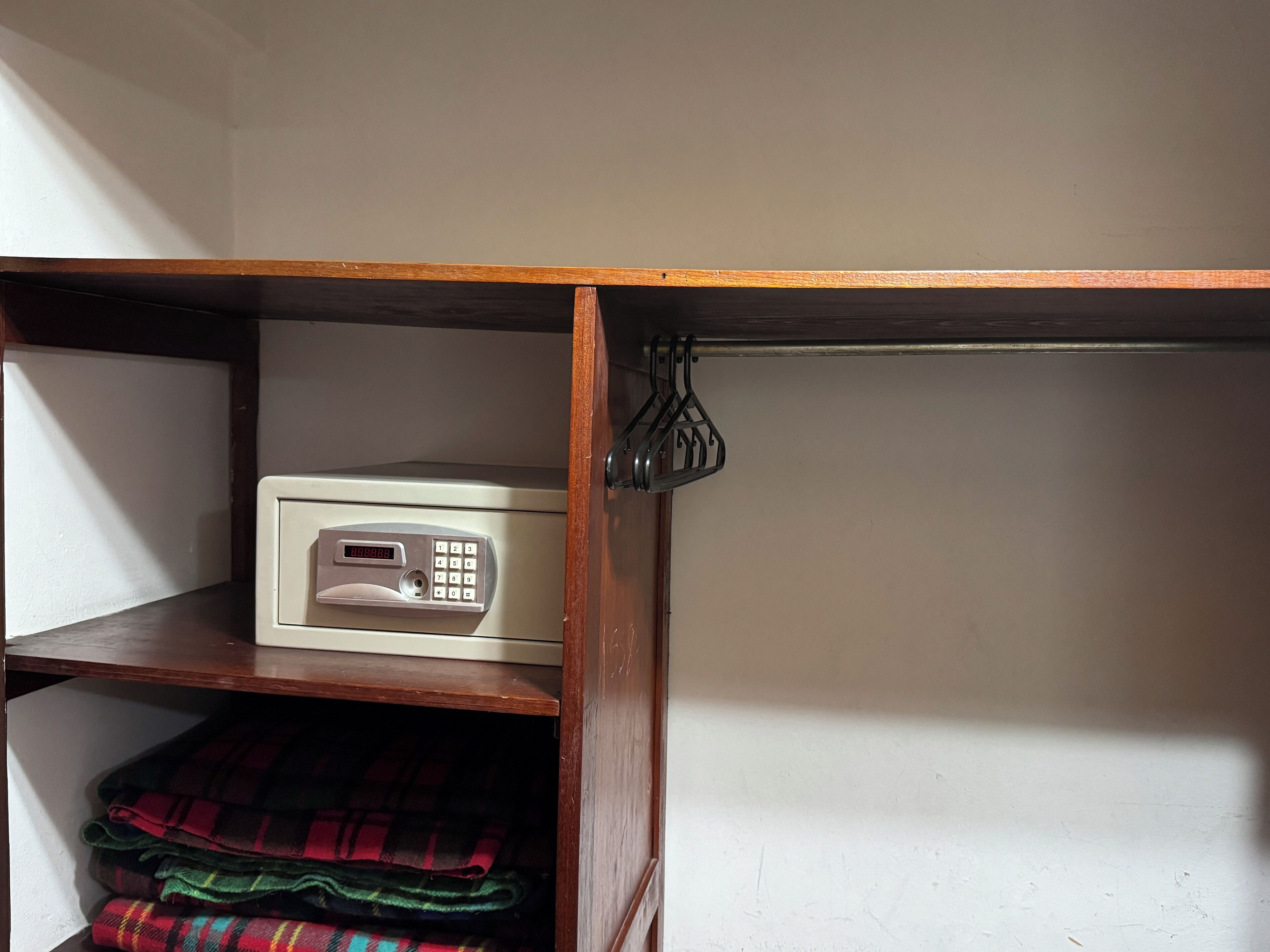 Eine Mikrowelle auf einem Regal mit Holzrahmen, eine gefaltete Karo-Decke und ein Metallhaken.