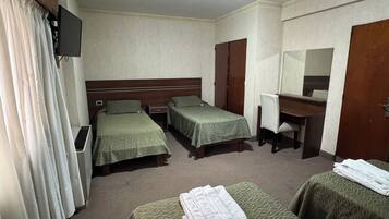 A hotel room with two single beds, a desk with a chair, a mirror, and a television on the wall.