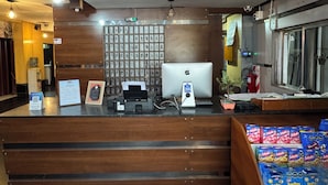A reception desk with a computer, a wall of framed photos, and a window with a view of the street. - Hotel Quebrada de Humahuaca (San Salvador de Jujuy)